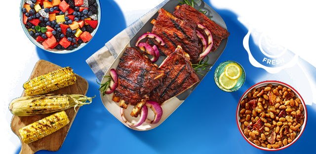 Spread of grilled ribs, grilled corn, fruit salad, baked beans and a beverage garnished with lemon wheels. Spread of grilled ribs, grilled corn, fruit salad, baked beans and a beverage garnished with lemon wheels.